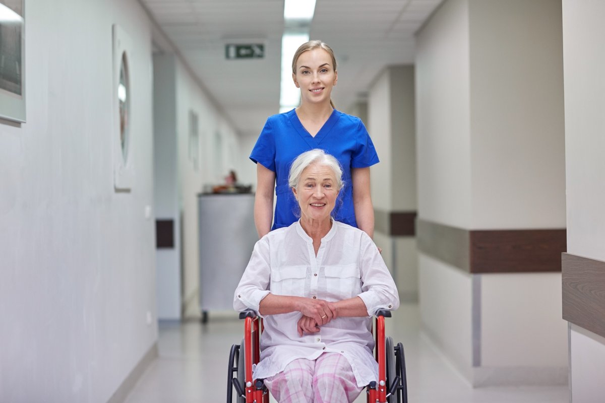 Verpleegkundige duwt patiënte in een rolstoel